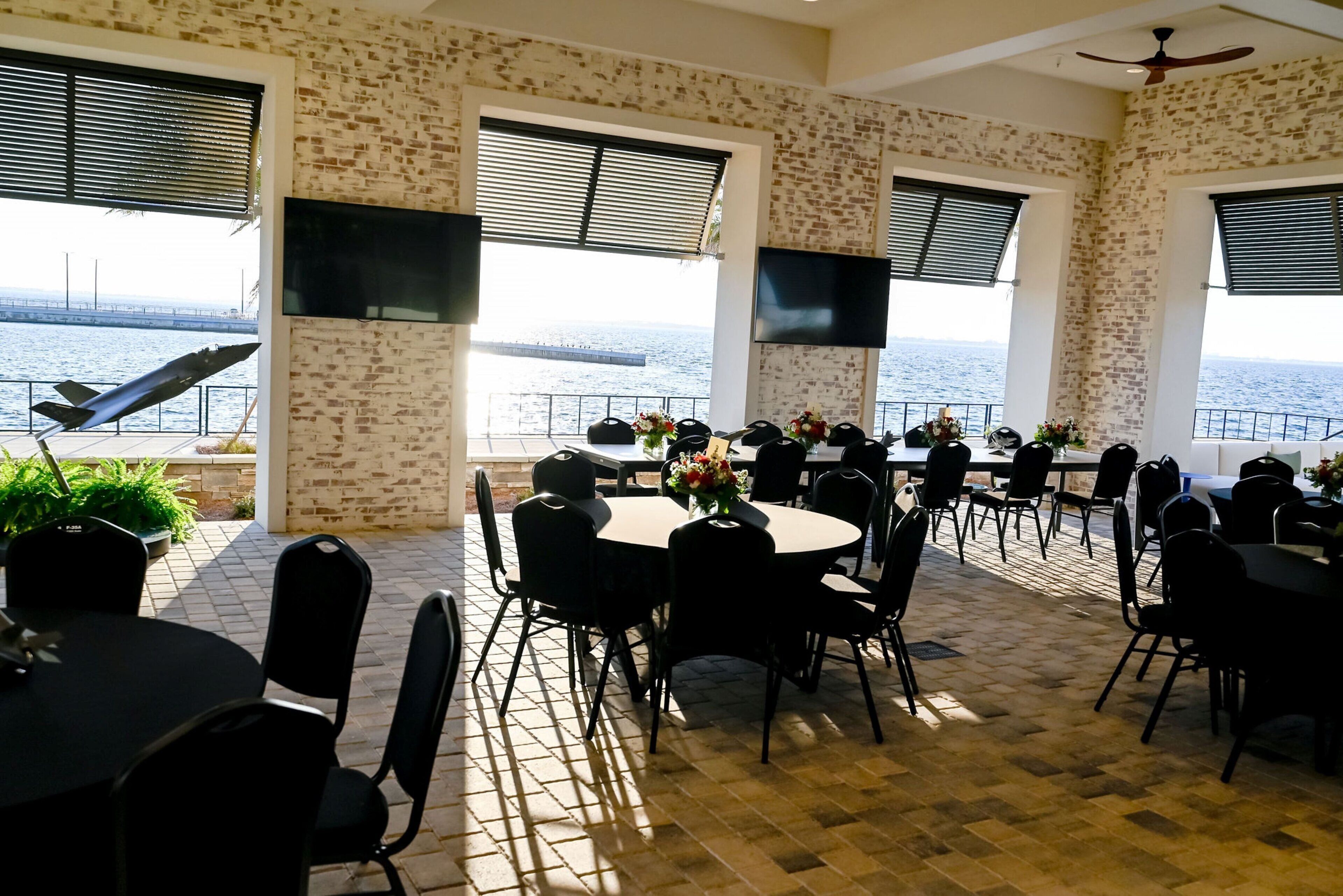 A dining area with brick walls, large windows, and a view of the sea.