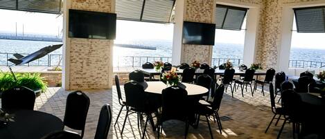 A dining area with brick walls, large windows, and a view of the sea.