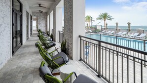 A balcony with a pool view, wicker chairs, and a ceiling fan. - Hotel Indigo Panama City Marina by IHG (Panama City)