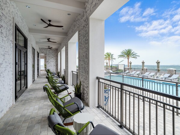 Ein Balkon mit Blick auf einen Pool, Korbstühle und einem Deckenventilator.
