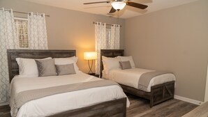A bedroom with two beds, wooden headboards, a ceiling fan, and a nightstand with a lamp. - Beautiful home away from home  (Raleigh)