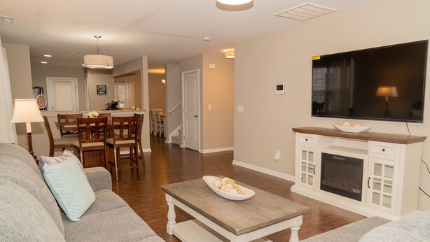 A living room with a fireplace, a television, and a dining area in the background. - Beautiful home away from home  (Raleigh)