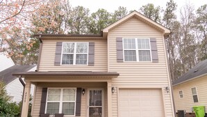 A two-story house with a garage, a front porch with chairs, and a small front yard. - Beautiful home away from home  (Raleigh)