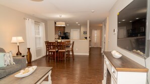 A modern living room with a sofa, coffee table, and dining area with chairs and a table. - Beautiful home away from home  (Raleigh)