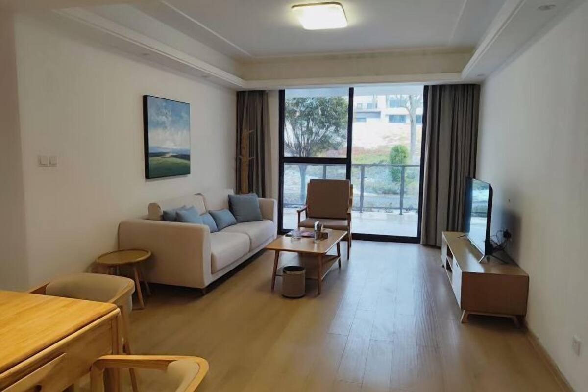 A spacious living room with a sofa, coffee table, and TV stand.