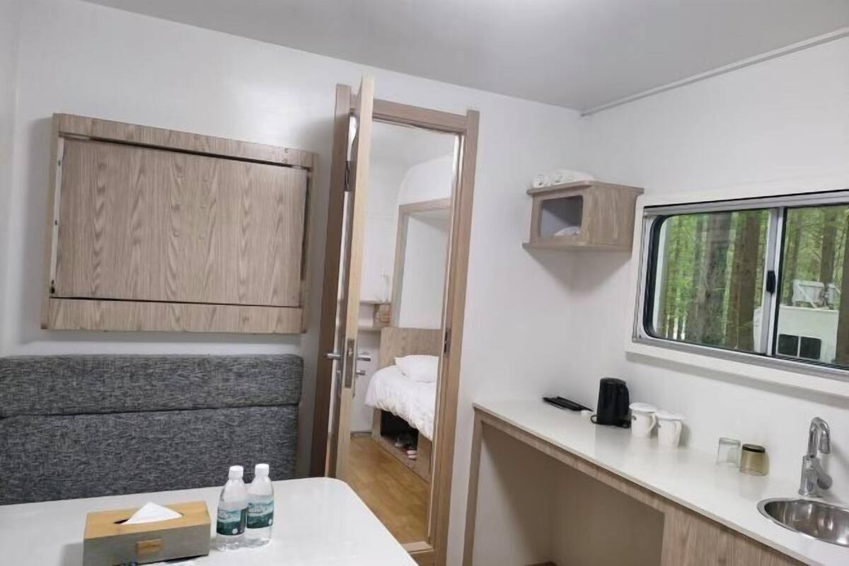 A compact kitchenette with a sink, a mirror, and a window.