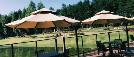 Mobiliario exterior con sombrillas, piscina y campo de golf al fondo.