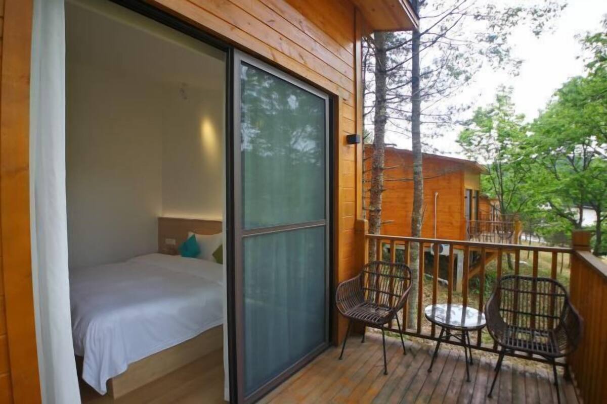 A bedroom with a bed, a sliding glass door, and a balcony with chairs and a table.