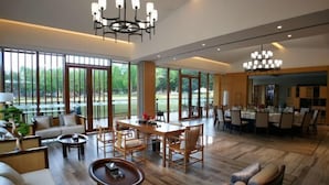 A spacious living area with a dining table, sofas, and a large window offering a view of greenery. - Zhaojun Champaign road Hotel (Xingshan)