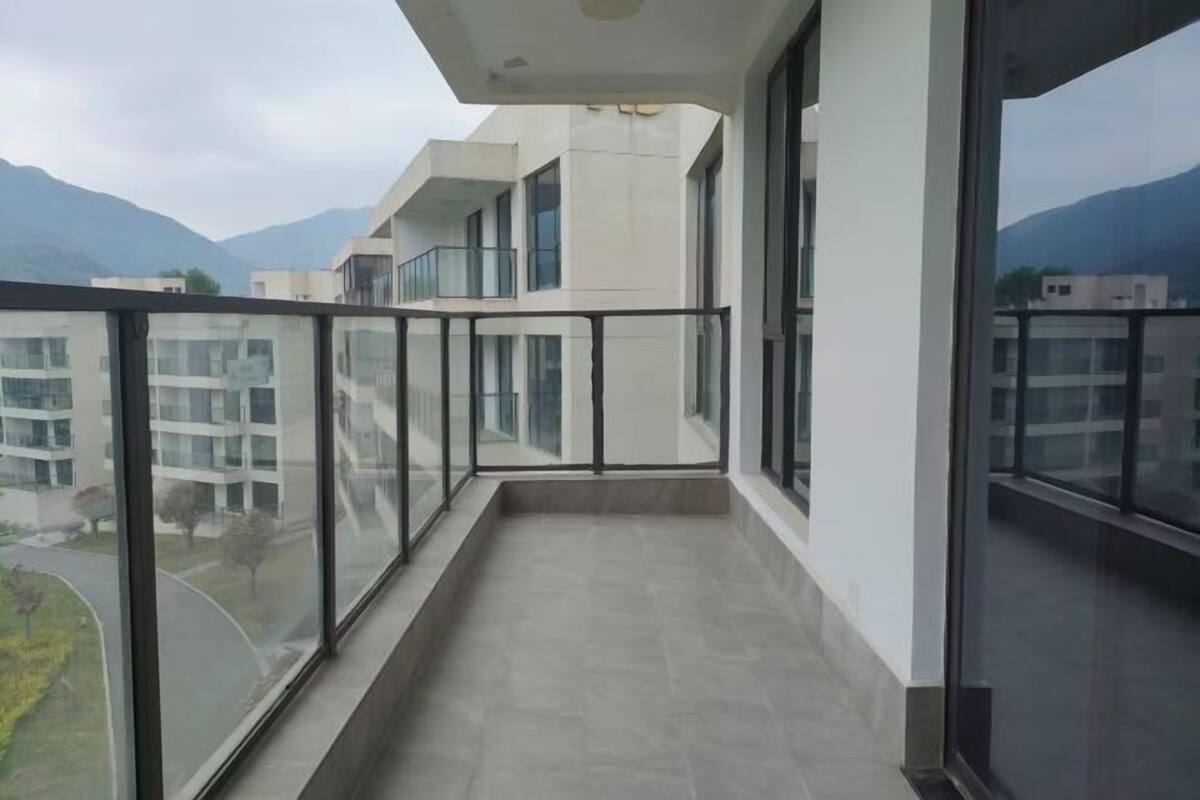 A modern building with a balcony overlooking a road and mountains.