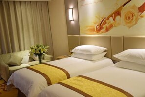 A hotel room with two beds, a sofa, a vase of flowers, and a wall with a floral design. - Vienna Hotel (Dongtai Chengdong New District) (Dongtai)