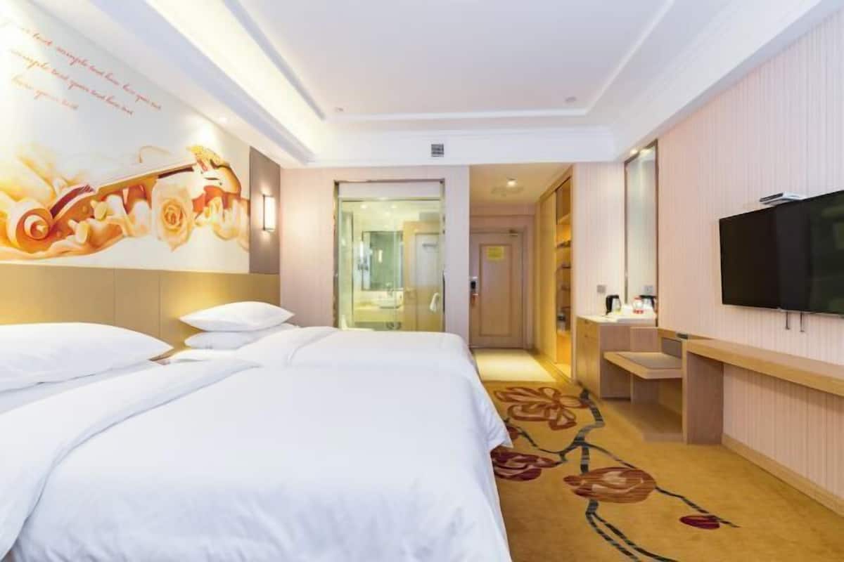A hotel room with a bed, a TV, a bathroom, and a hallway.