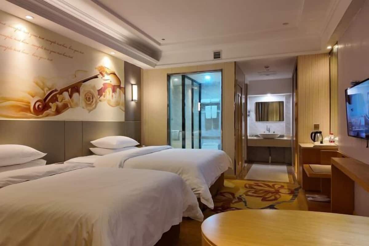 A hotel room with two beds, a bathroom with a sink, a television, and a decorative wall.
