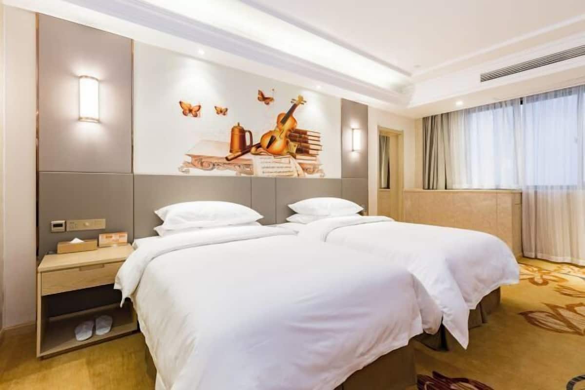 A hotel room with two beds, a wall-mounted artwork, a nightstand, and a window with curtains.