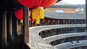 A traditional building with curved wooden architecture and red lanterns. - Yuqinglou Inn (Longyan)