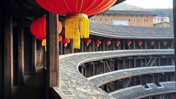 A traditional building with curved wooden architecture and red lanterns.
