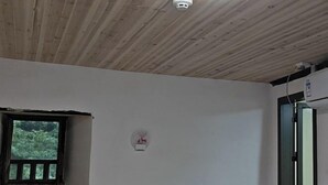 A room with a wooden ceiling, a window with a view of greenery, and a door with a mirror. - Yuqinglou Inn (Longyan)