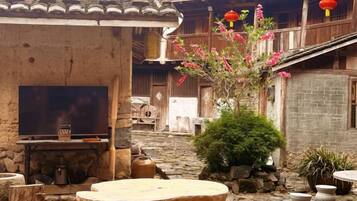 Un patio tradicional con muro de piedra, una mesa de madera y una planta en maceta.
