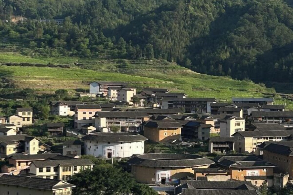 A cluster of traditional buildings with flat roofs and a hilly backdrop.