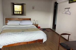 A bedroom with a wooden bed, a nightstand, a small window, and a chair. - Yuqinglou Inn (Longyan)
