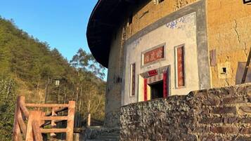 Un edificio tradicional con base de piedra y estructura superior de madera, con una puerta roja y señalización.