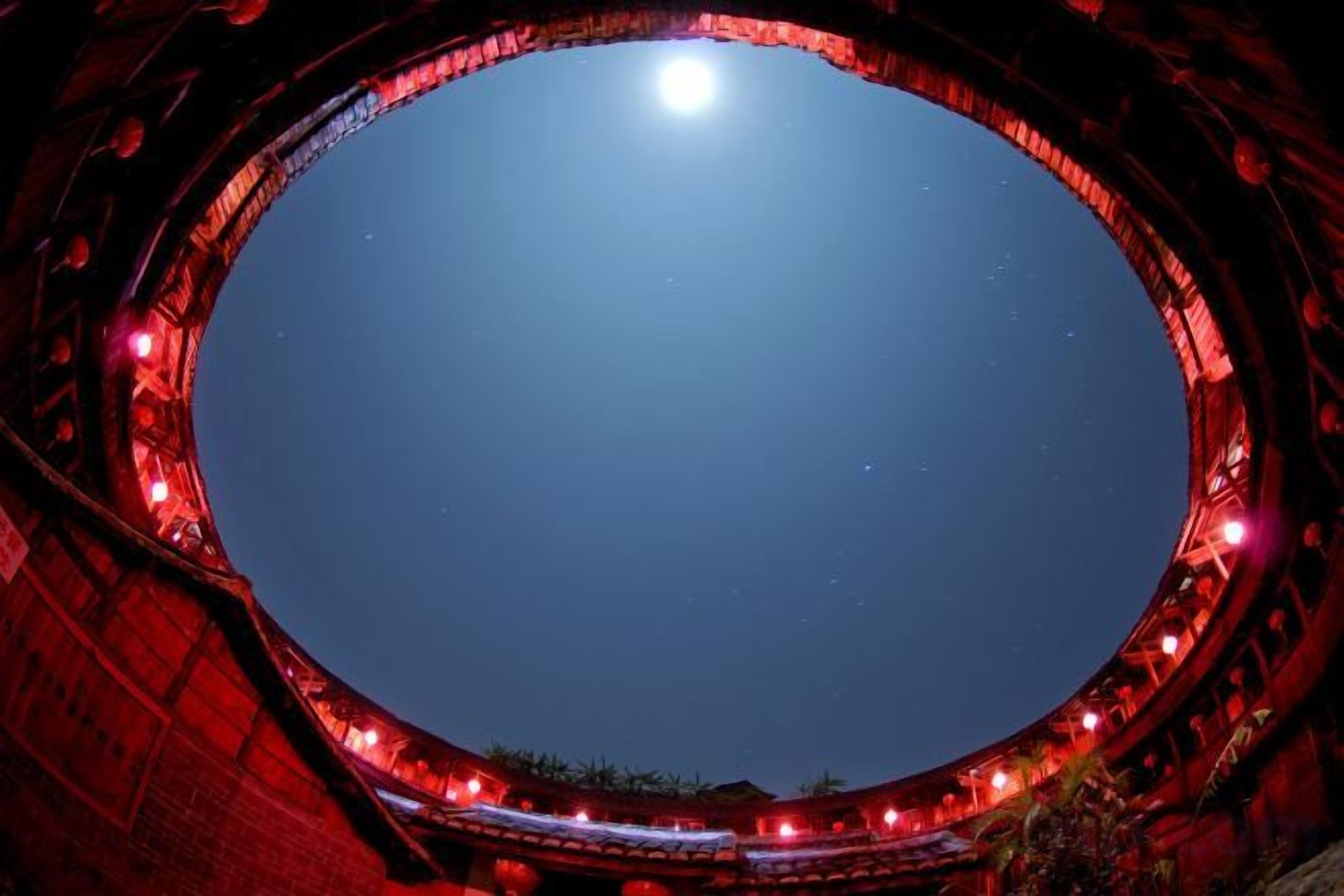 A circular architectural structure with a clear sky and a moon visible through the center.