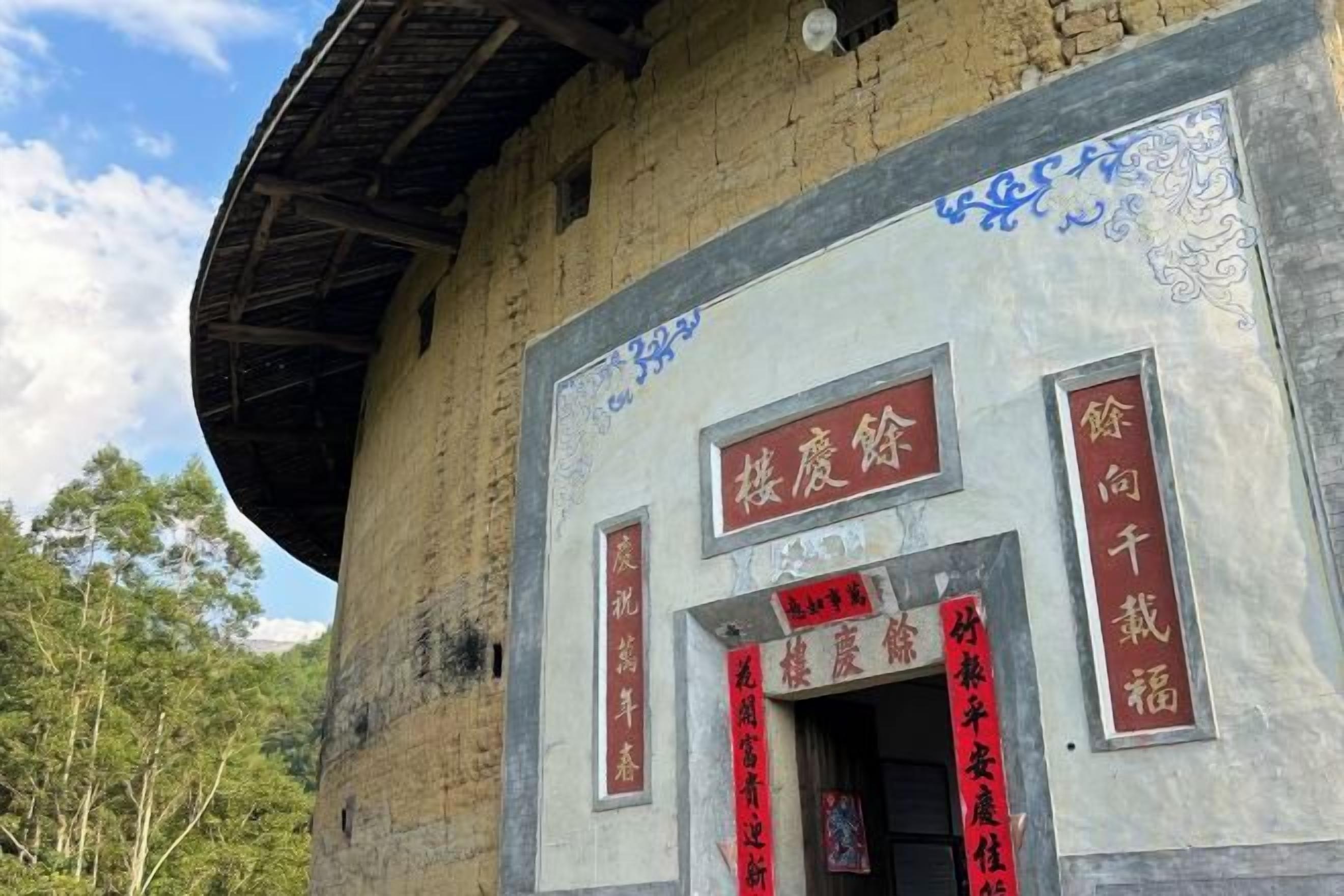 Un bâtiment à l’architecture chinoise traditionnelle, caractérisé par un toit circulaire et une entrée centrale ornée de caractères chinois rouges.