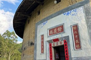 A building with traditional Chinese architecture, featuring a circular roof and a central entrance with red Chinese characters. - Yuqinglou Inn (Longyan)