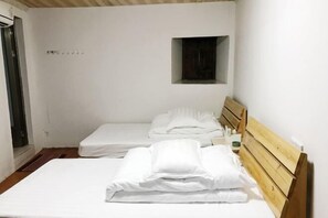 A small, clean room with two single beds, a wooden headboard, a small window, and a door. - Yuqinglou Inn (Longyan)
