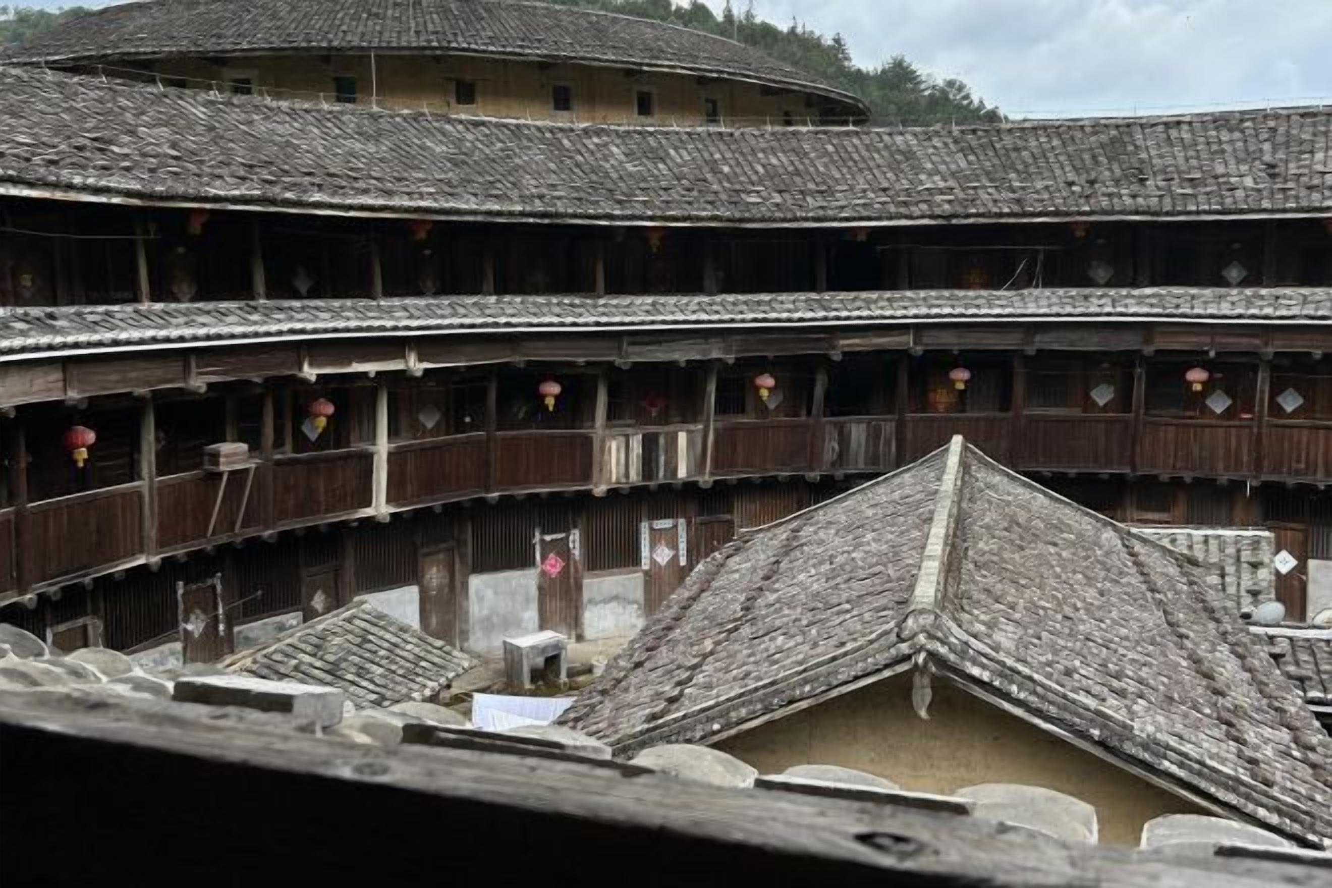 Un edificio tradicional de madera de varios pisos, con un techo curvo, balcones con faroles rojos y un patio.