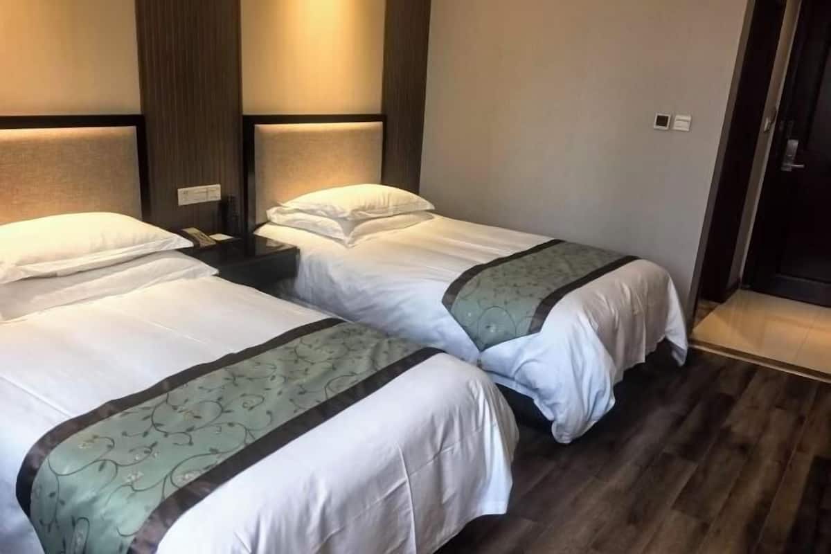 A hotel room with two beds, wooden flooring, and a modern design.