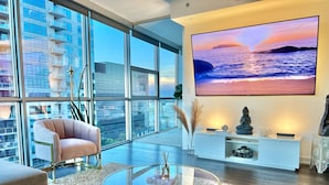 Una sala de estar moderna con un televisor grande, asientos cómodos y vistas a la ciudad.