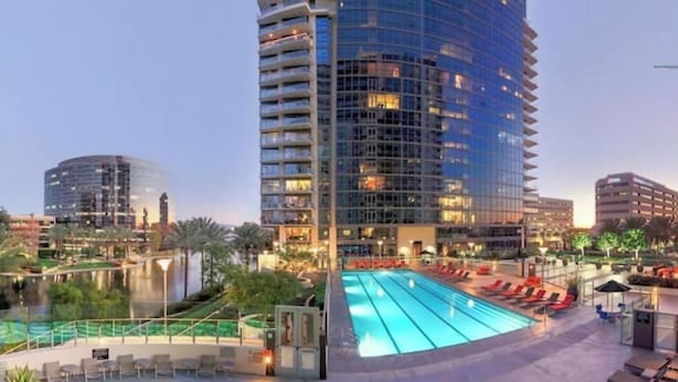 Un hotel con piscina, sillones de descanso y vistas a la ciudad.