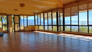 Una habitación amplia con ventanas grandes, piso de madera y vistas a las montañas.