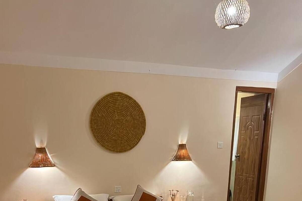 Un dormitorio con una cama grande, dos lámparas de noche, un adorno redondo en la pared y una puerta de madera.