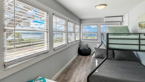 A compact room with a bunk bed, large windows with blinds, a black bean bag, and a ceiling light. - Anchors Away River House (St. Augustine)