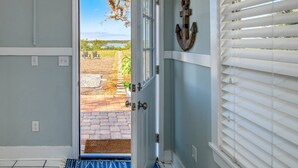 A door leading to a patio with a view of a grassy area and a body of water. - Anchors Away River House (St. Augustine)