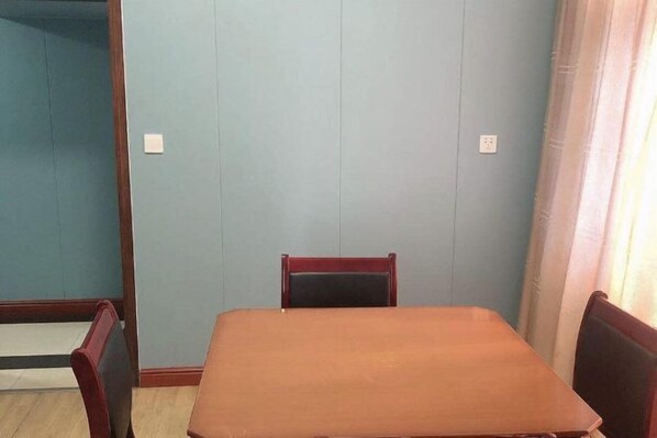 A room with a wooden table and two chairs, light blue walls, and a window with curtains. - Shuangfeng Century Hotel (Shuangfeng)