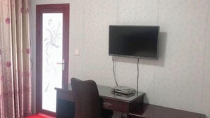 A room with a TV mounted on the wall, a desk with a chair, and a door with a frosted glass panel. - Shuangfeng Century Hotel (Shuangfeng)