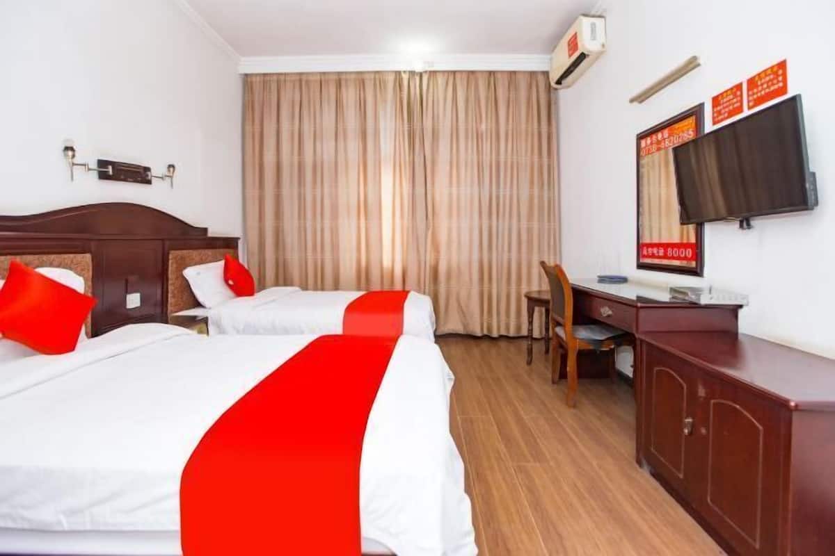 Habitación de hotel con dos camas, un escritorio, una silla, un televisor y un armario.