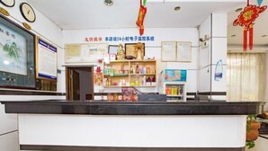 A reception area with a counter, shelves with various items, and a wall with certificates and notices. - Shuangfeng Century Hotel (Shuangfeng)
