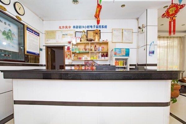 A reception area with a counter, shelves with various items, and a wall with certificates and notices. - Shuangfeng Century Hotel (Shuangfeng)