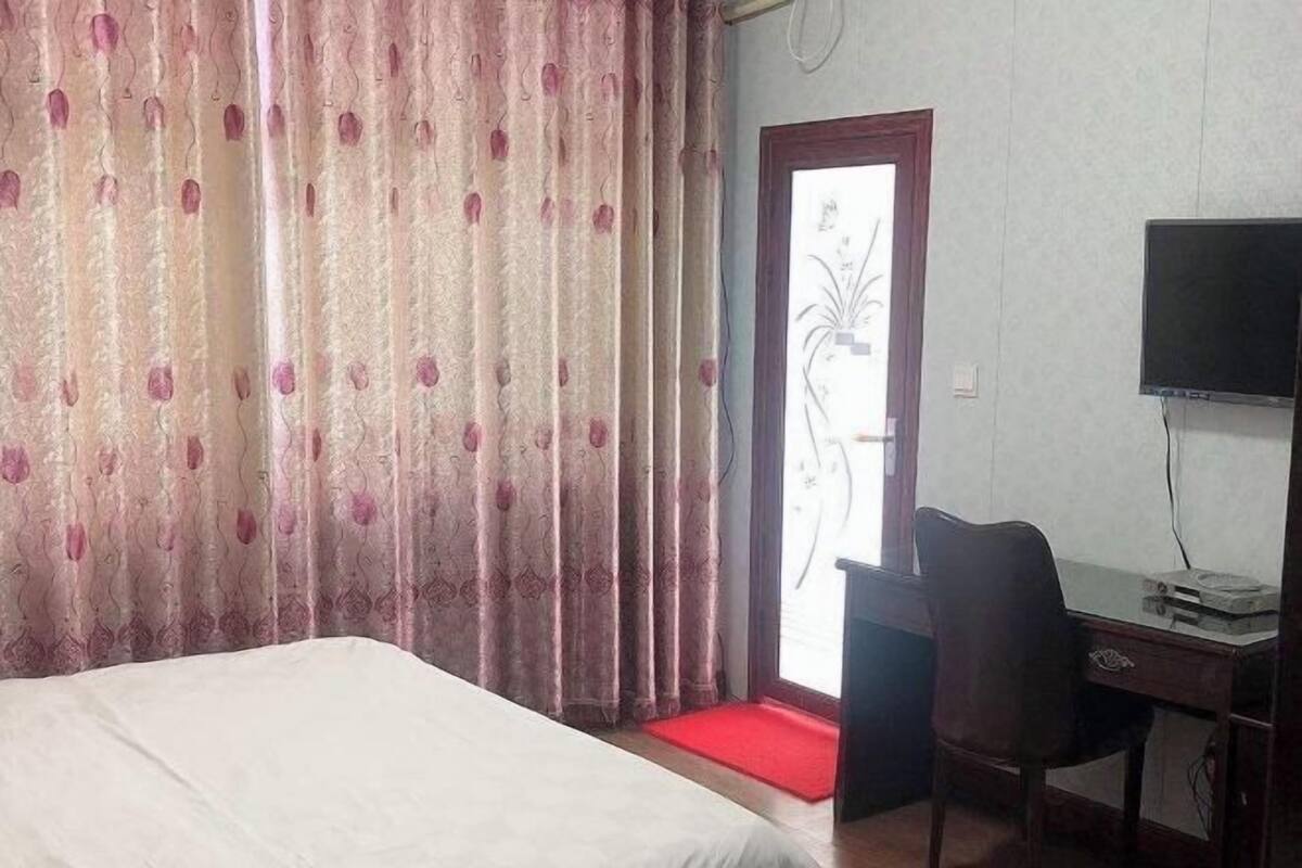 Una habitación de hotel con cama, un escritorio con silla, una televisión y una puerta con felpudo rojo.