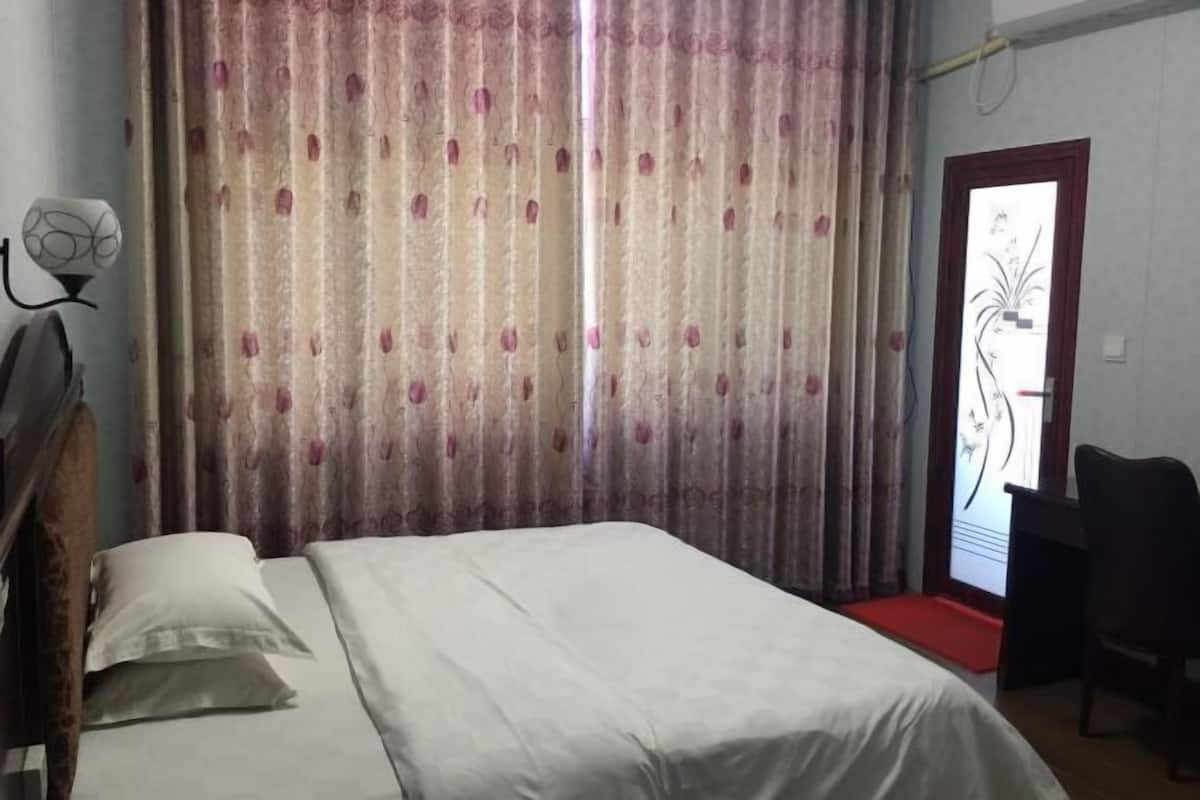 Una habitación con una cama, un escritorio, una silla y una puerta decorada con motivos florales.