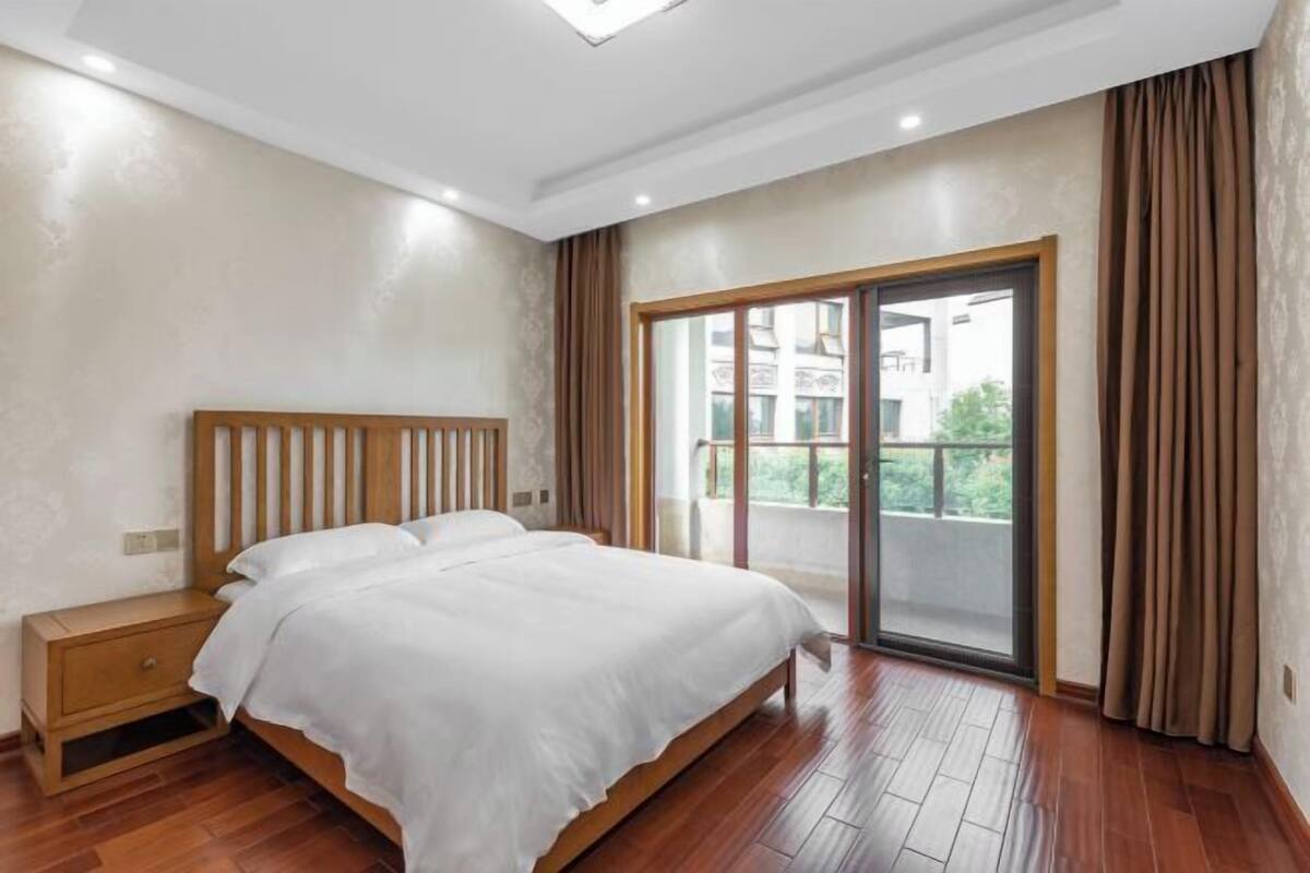Un dormitorio con cama, mesita de noche de madera y una puerta corrediza de vidrio que da a un balcón.