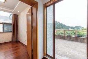 Une pièce dotée d’un plancher en bois, d’une porte-fenêtre coulissante et donnant sur un balcon avec une balustrade.