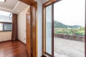 Una habitación con piso de madera, un ventanal corredero y vistas a un balcón con barandilla.