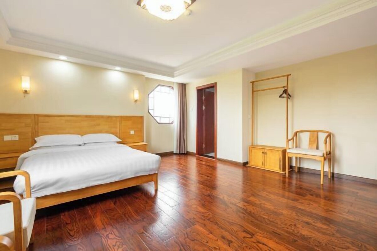 Une chambre avec un lit en bois, une table de chevet en bois, une chaise et une armoire.