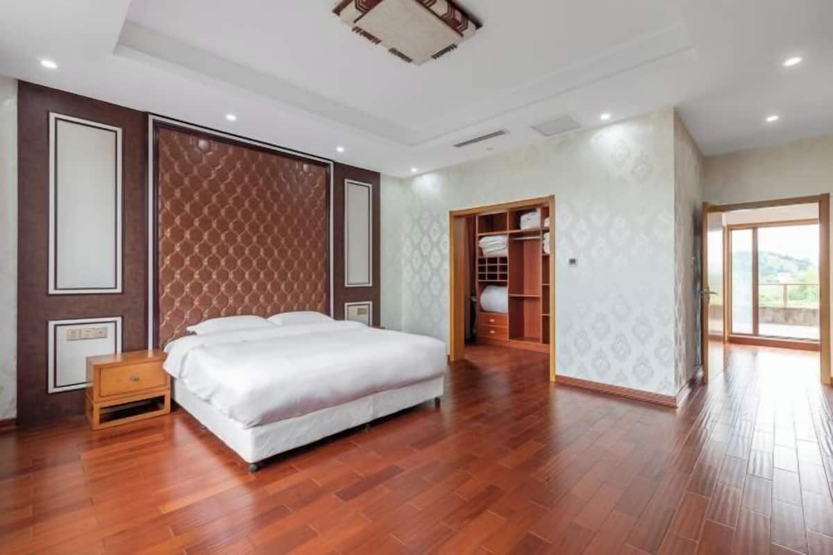 Un dormitorio con cama, suelo de madera, armario y vistas a través de una puerta.