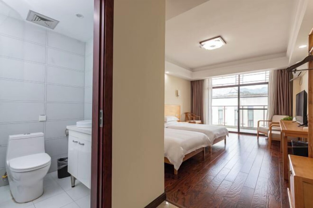 Une chambre d’hôtel avec salle de bain, deux lits, un bureau et vue sur un pont.